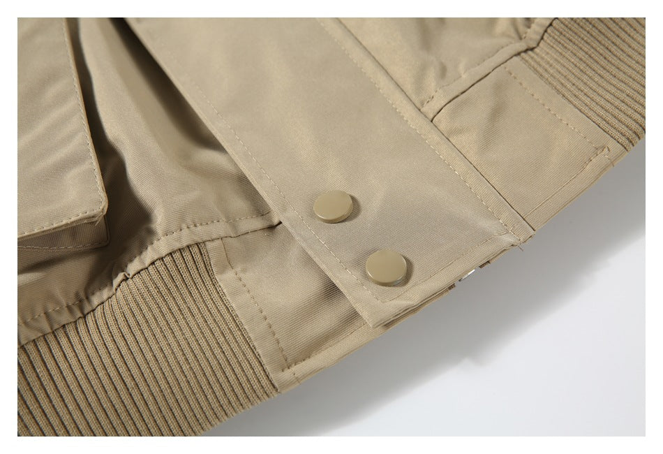 Close-up of beige jacket cuff with two snaps and ribbed trim.
