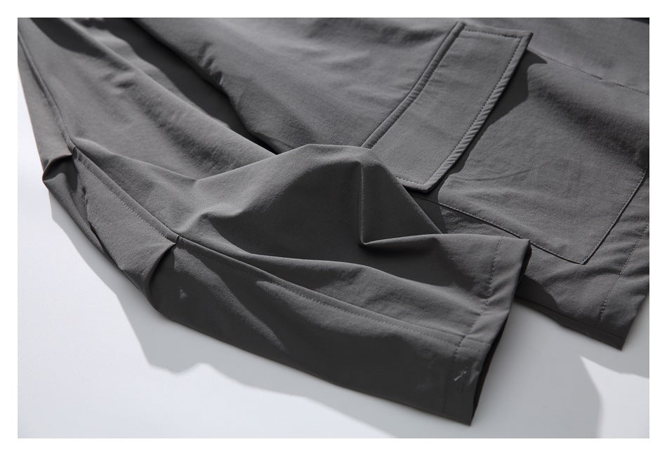 Close-up of the charcoal jacket's sleeve cuff and chest pocket on a white background.