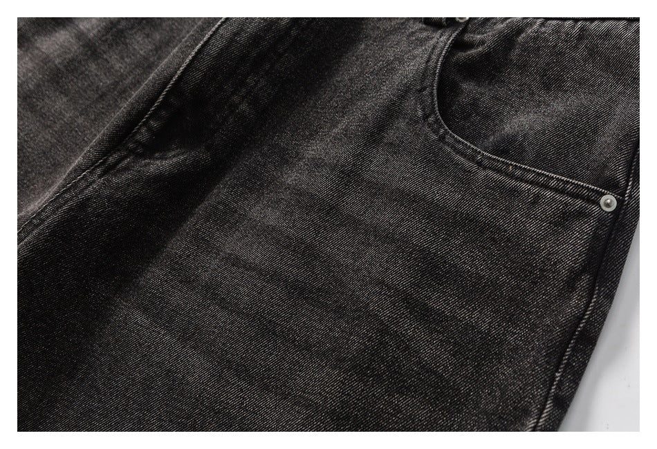 Close-up of the front pocket and metal rivet on charcoal washed jeans.