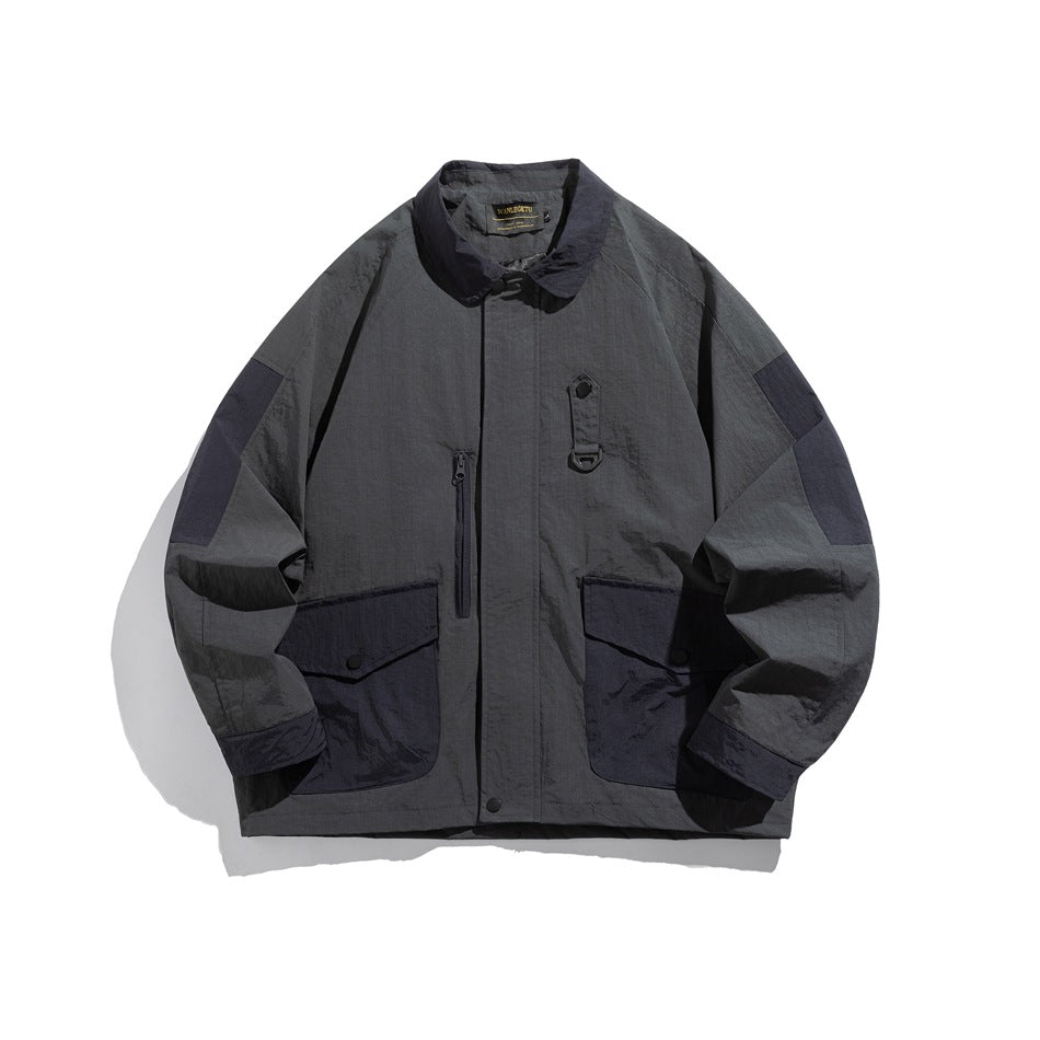 Dark gray collared jacket with navy contrast pockets, shoulder panels and cuffs, front view on white