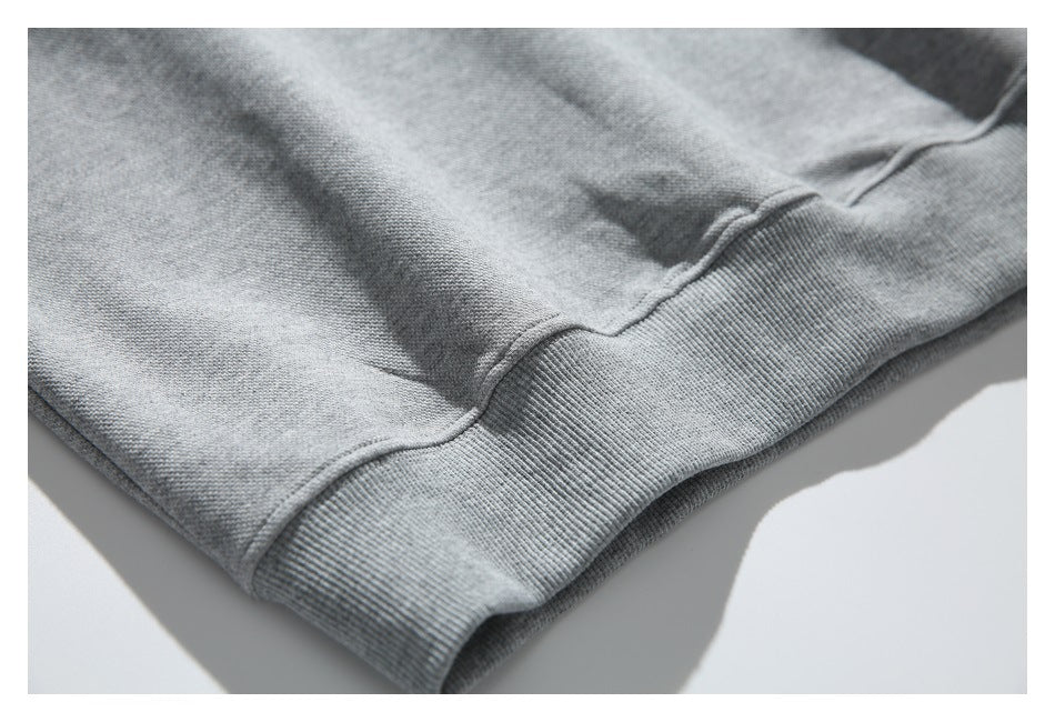 Angled close-up of the gray sweatshirt's ribbed waistband and hem stitching.