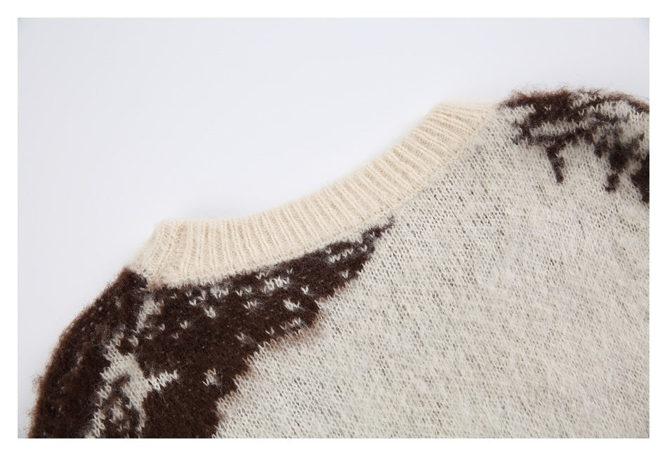 Close-up of the cream ribbed neckline and shoulder of a sweater with dark brown patterning.