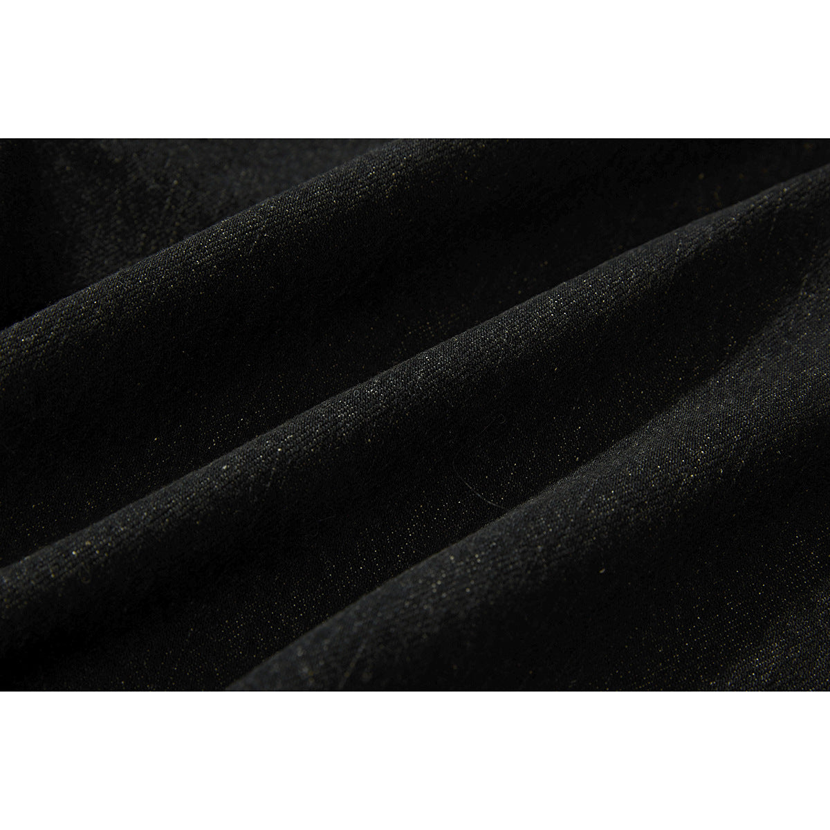 Close-up of dark denim fabric arranged in soft folds, showing its woven texture.