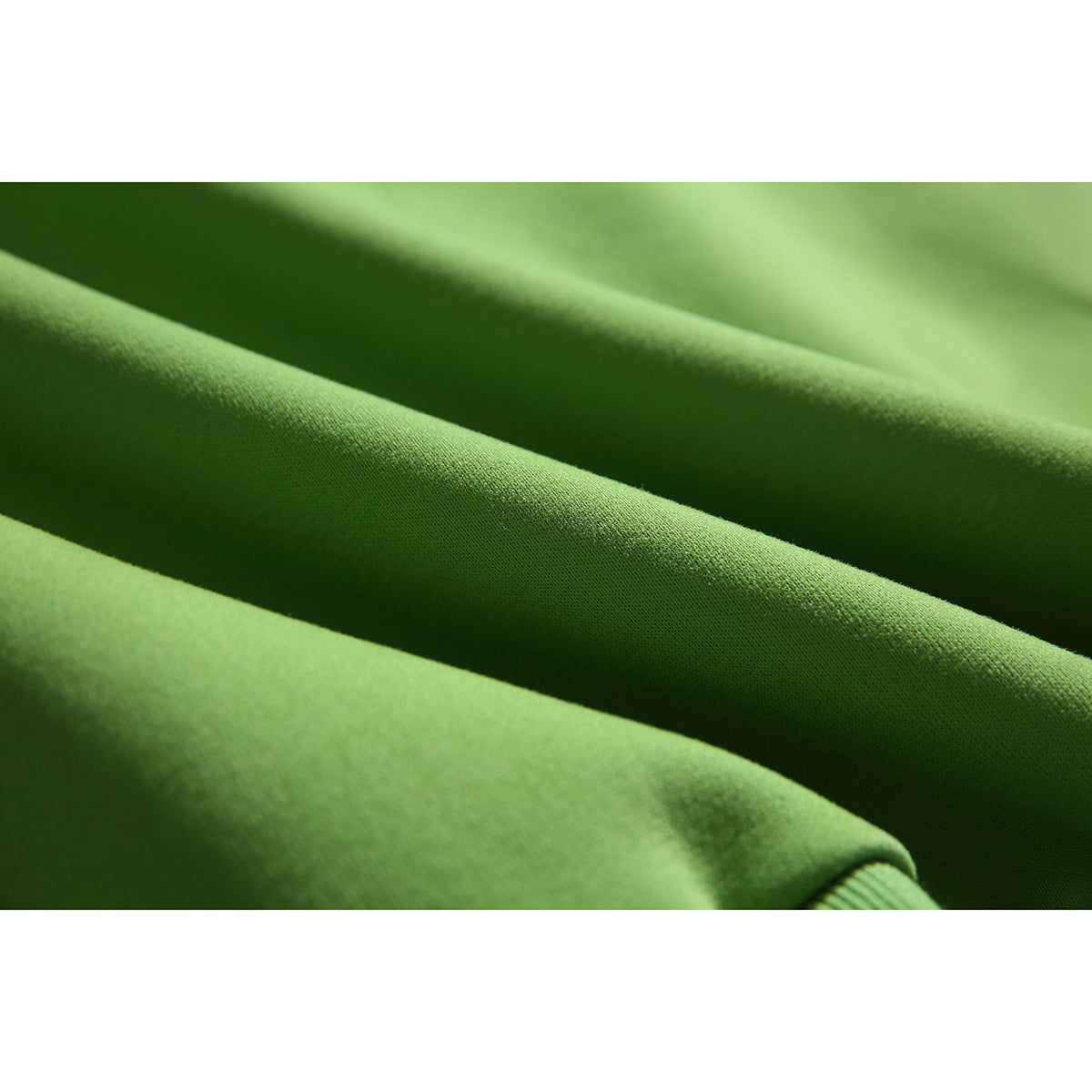 Extreme close-up of the green sweatshirt fabric, showing its surface texture and a small portion of the ribbed cuff.