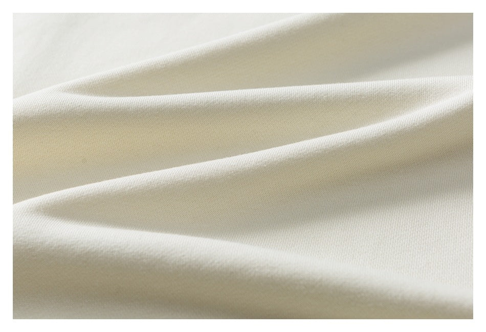 Close-up of smooth ivory fabric draped in soft folds, showing its fine knit texture.