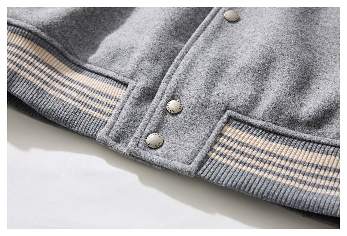 Close-up of a gray jacket with metal buttons and striped ribbed cuffs and hem.