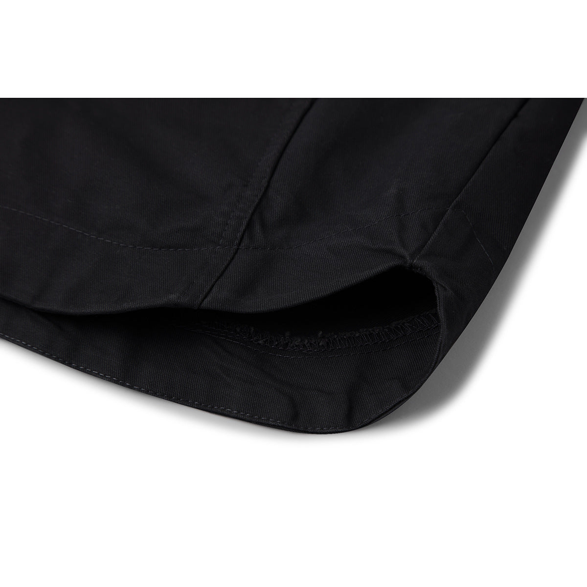 Close-up of the curved hem and stitched seams of a black shirt.