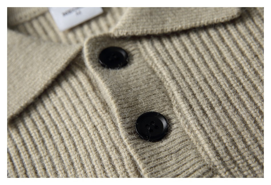 Close-up of two black buttons on the placket of a beige ribbed knit sweater.