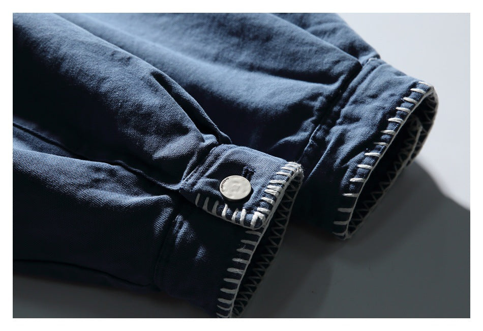 Close-up of a dark blue sleeve cuff with pale contrast stitching and a button.