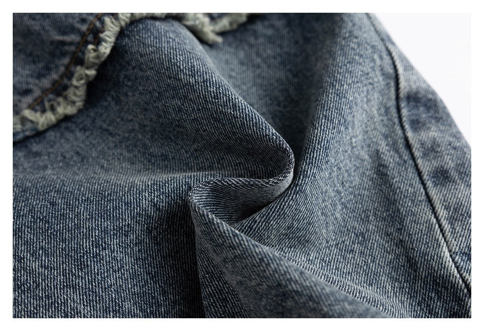 Macro view of textured blue-gray denim folded to show its diagonal weave and frayed edge.