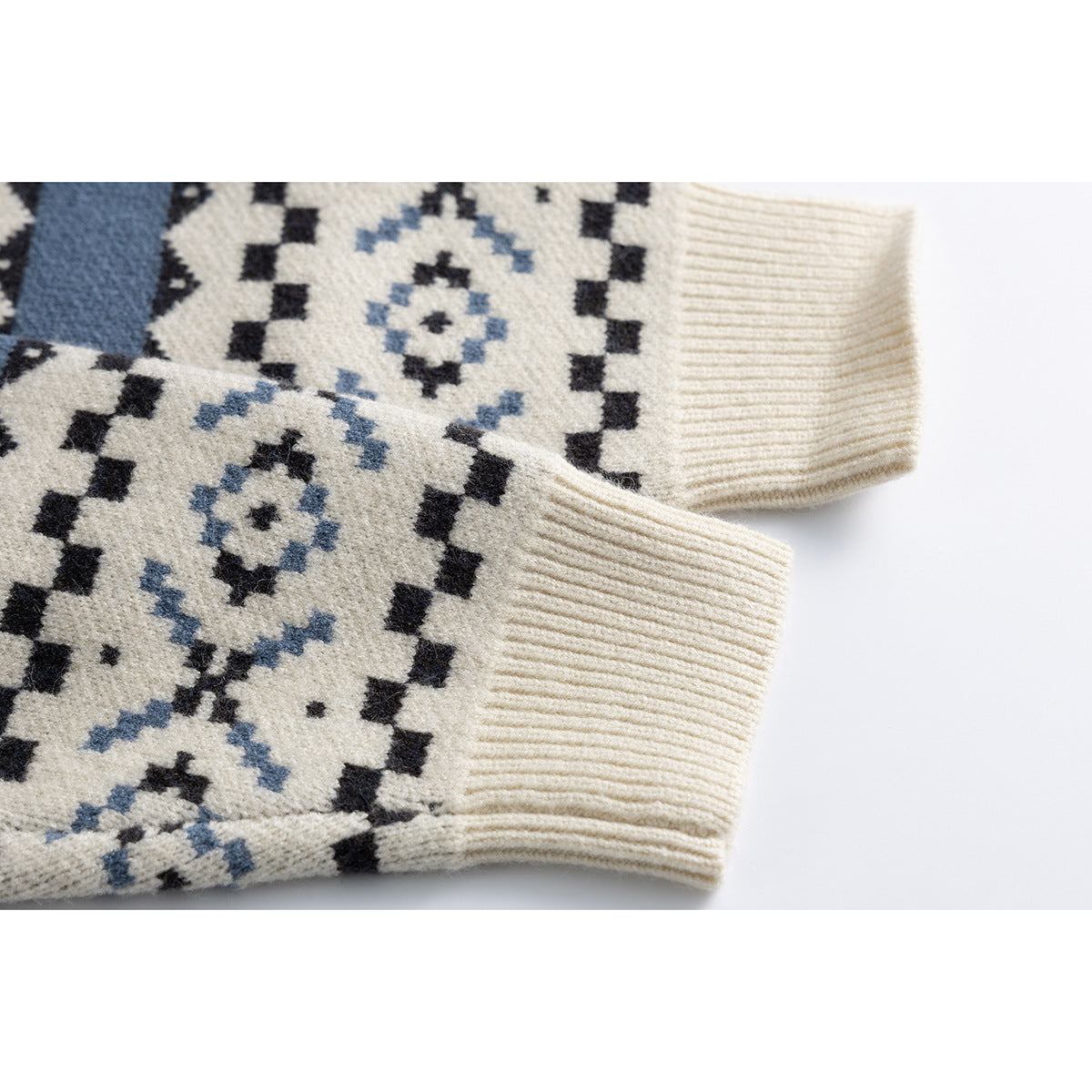 Close-up of the ivory sweater’s patterned sleeve and ribbed cuff against a white background.