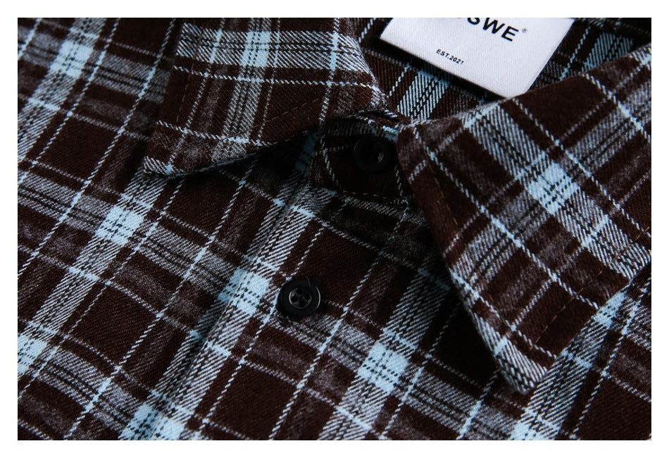 Close-up of the collar and black buttons on a brown and pale blue plaid shirt.