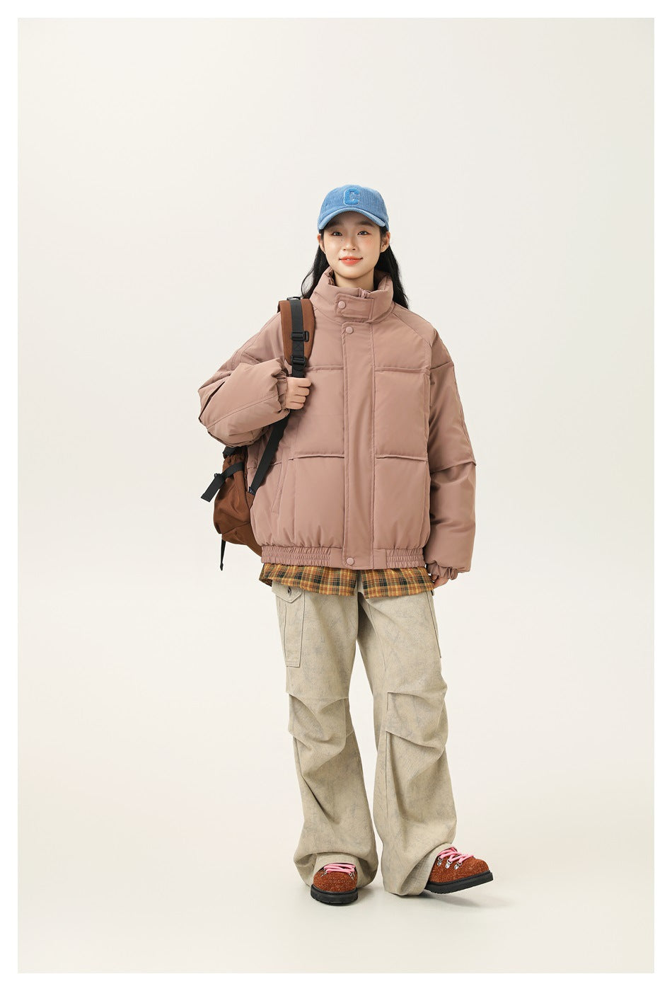 Full-length view of a woman wearing a dusty rose oversized jacket with a high collar and front pockets.