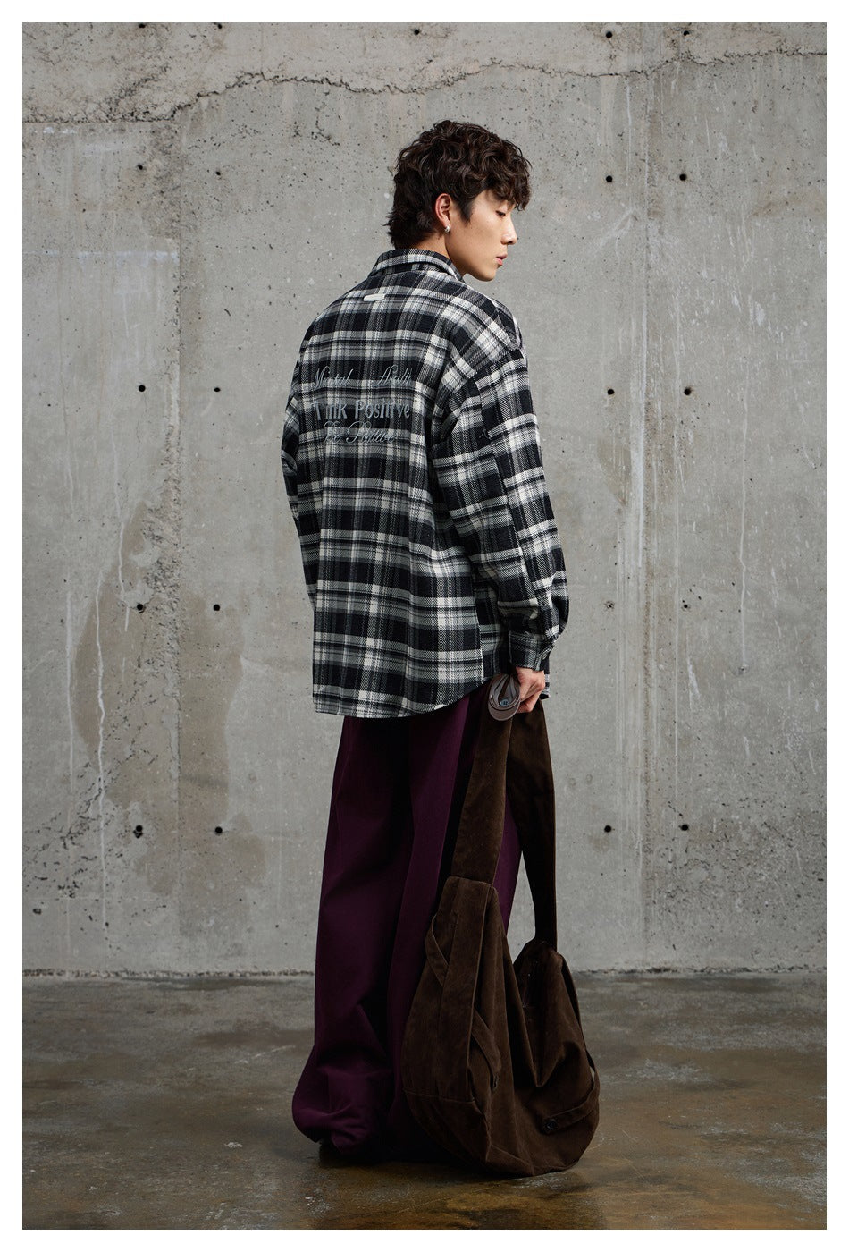 Model shown from behind in a black-and-white plaid shirt with white lettering across the back.