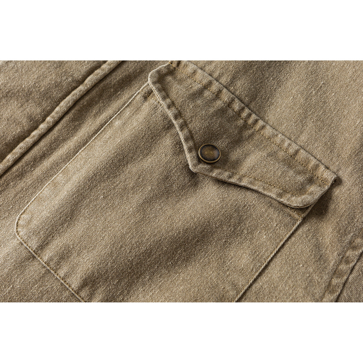 Close-up of a tan jacket's flap chest pocket with a dark metal snap.