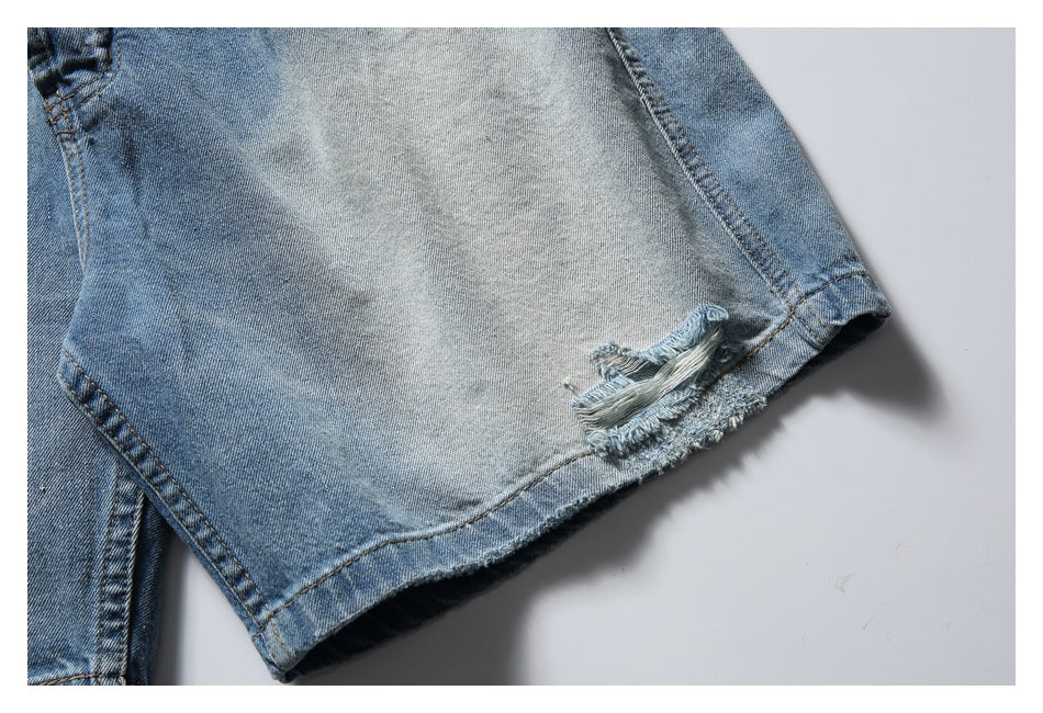 Close-up of a light blue denim shorts leg with a distressed rip and frayed hem.