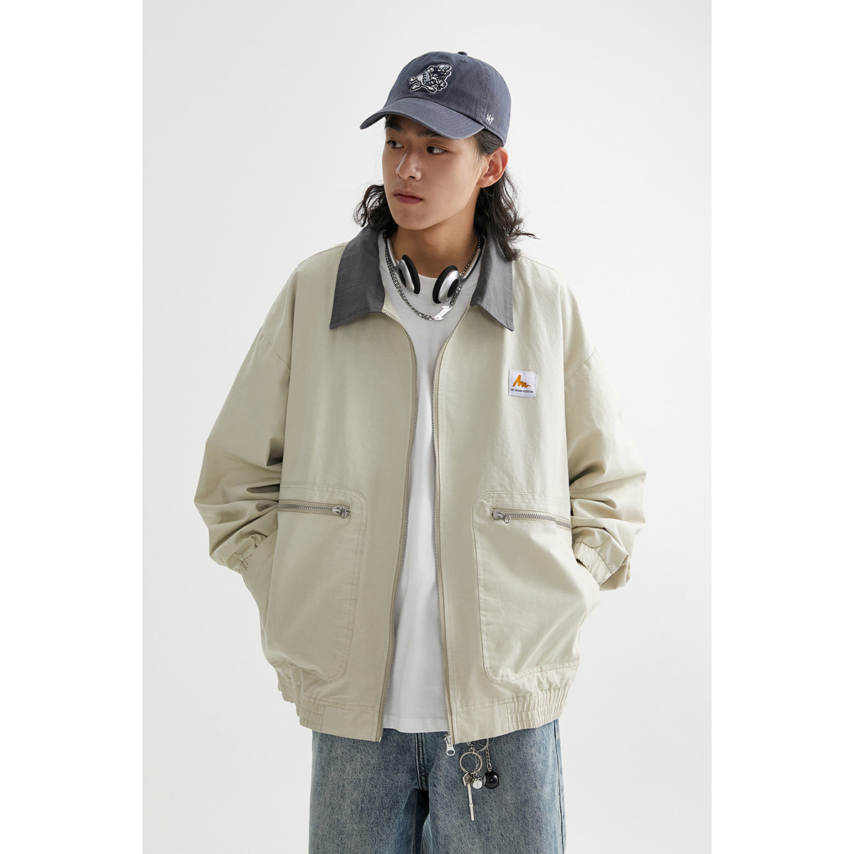 Model wearing a light beige zip-front jacket with a dark gray collar, elastic cuffs, and two zip pockets.