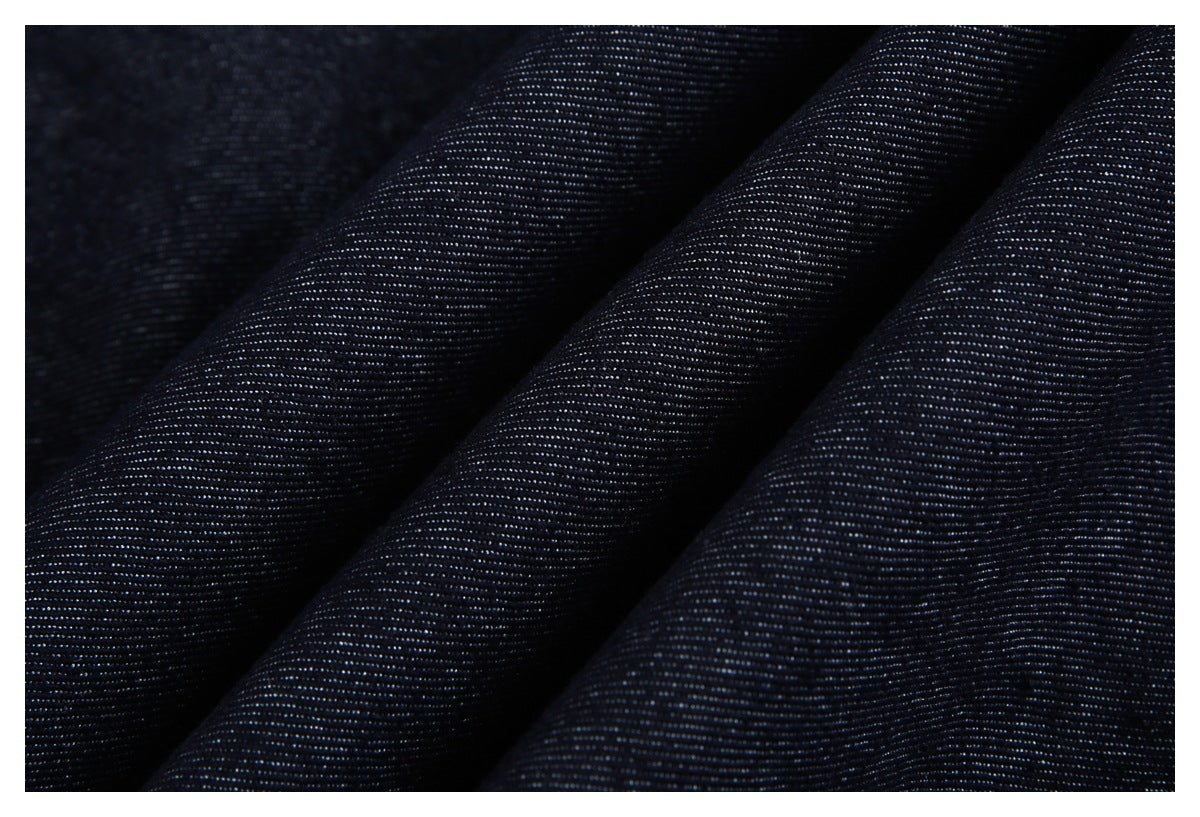 Extreme close-up of dark indigo fabric draped in folds, showing its fine woven texture.
