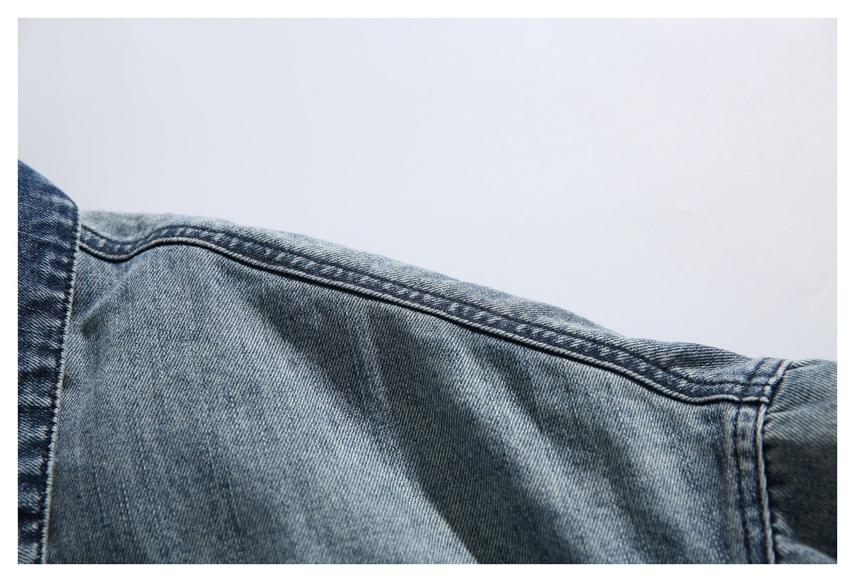 Close-up of a faded blue denim jacket shoulder seam and sleeve.