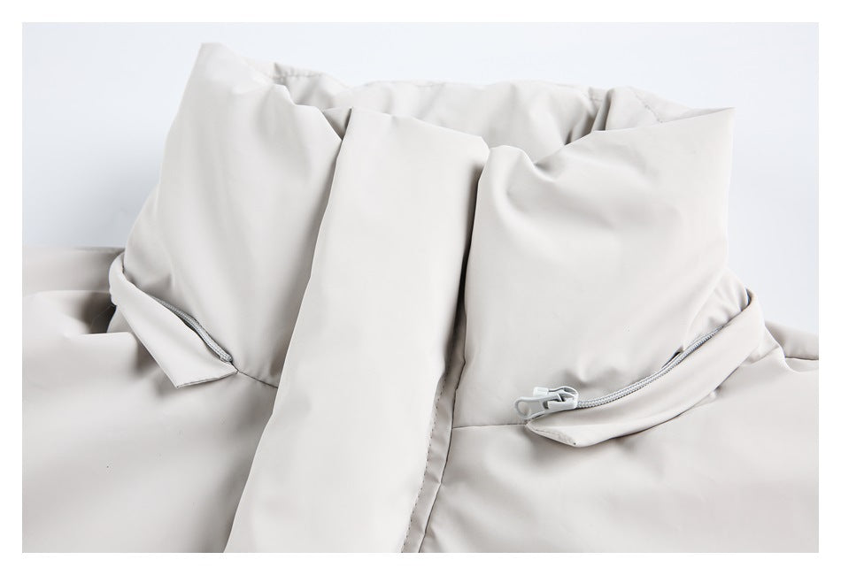 Close-up of the light beige coat's front panels and zippered pocket details.