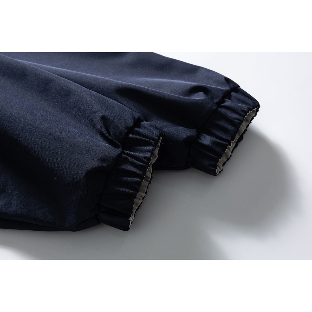 Close-up of gathered navy jacket cuffs with light lining visible at the edges.