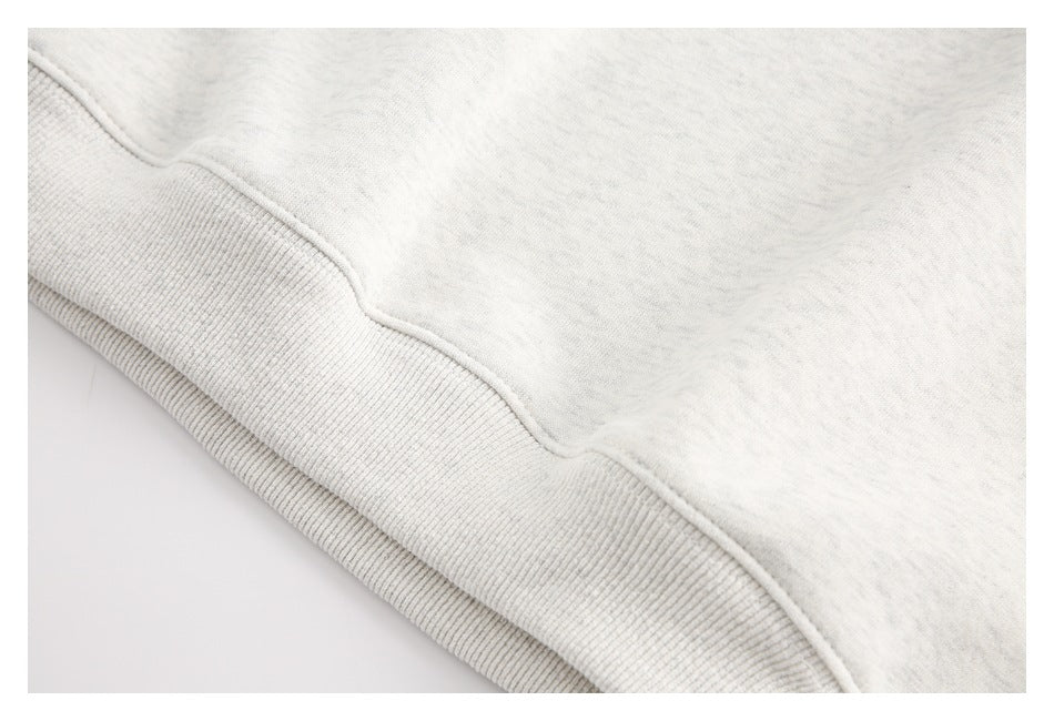 Close-up of the ribbed hem and seam on a light heather-gray sweatshirt.