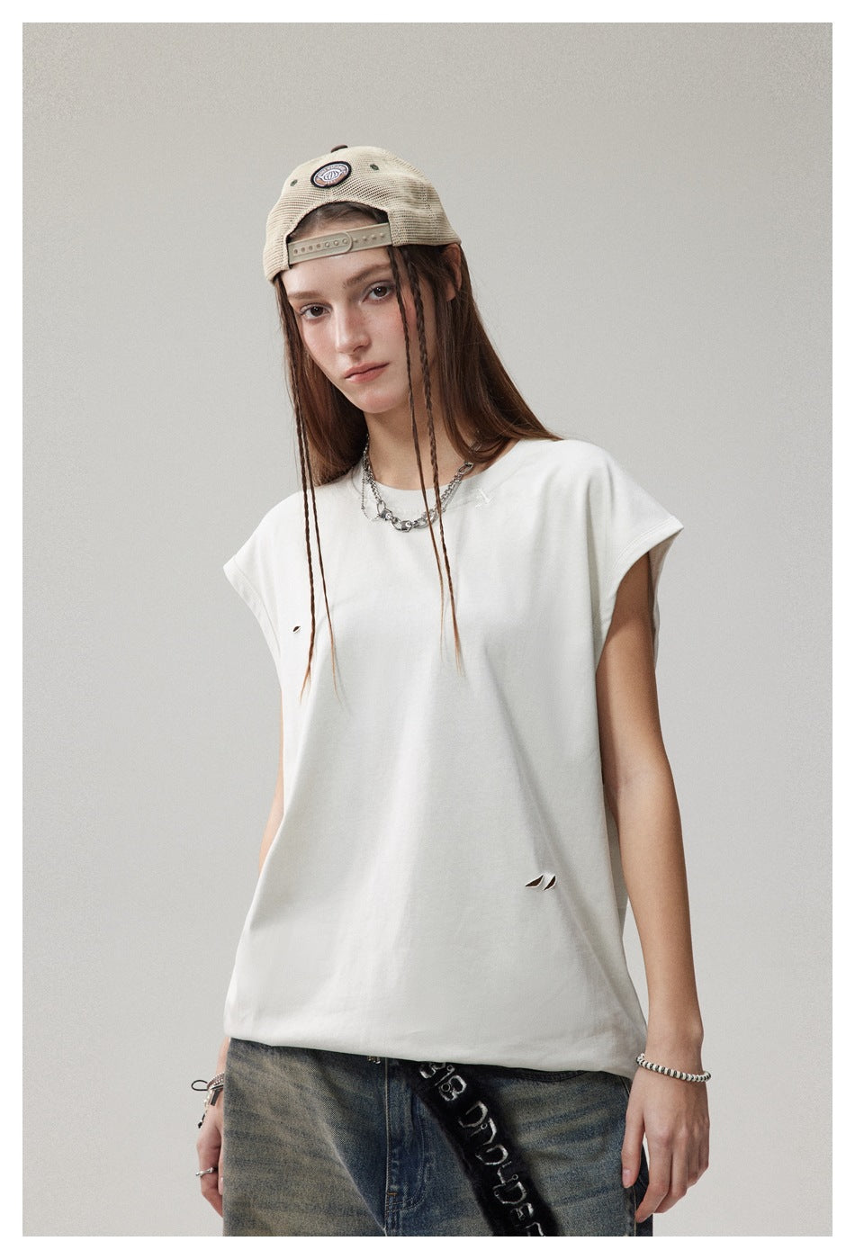Model wearing a loose white cap-sleeve T-shirt with small distressed slits, shown from the front.