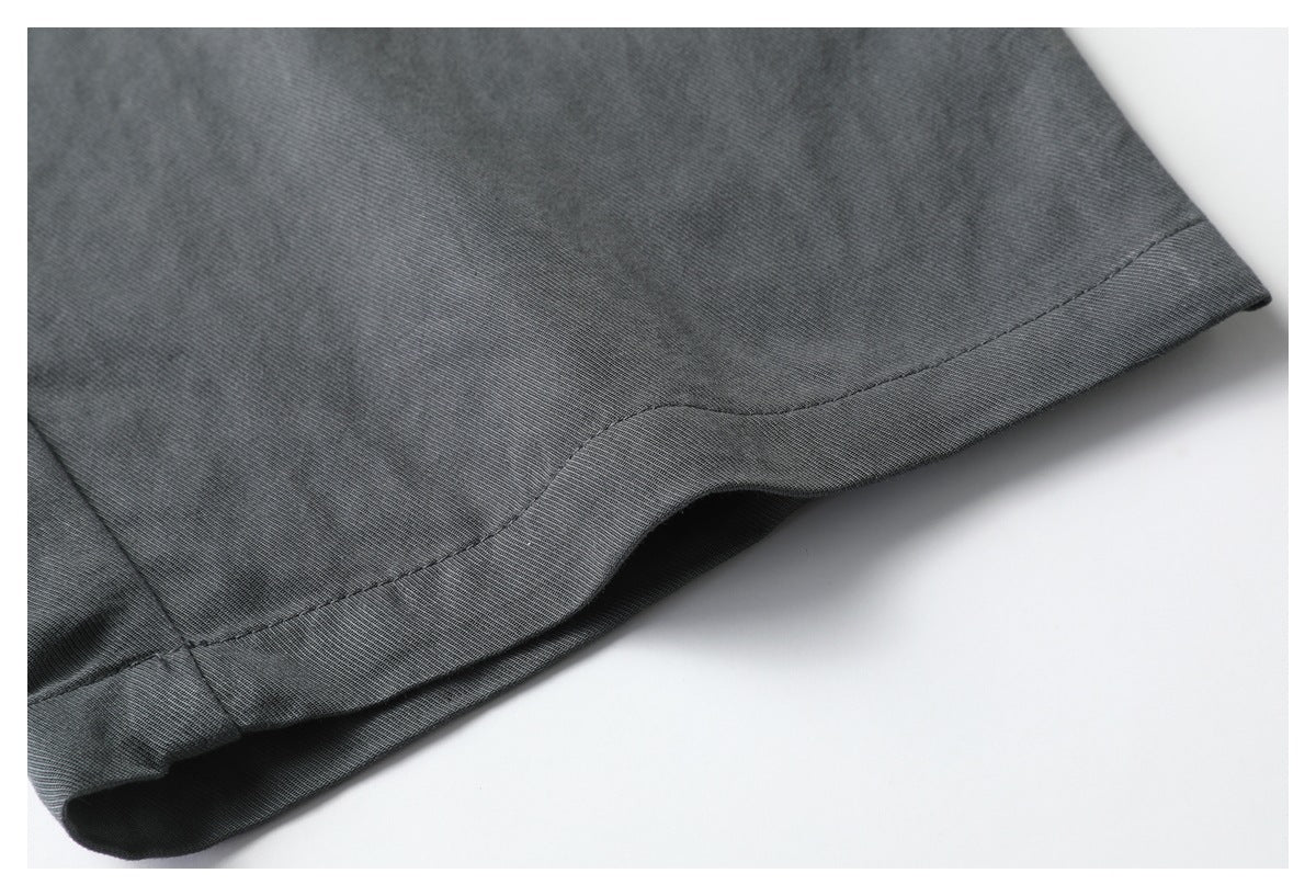 Close-up of the stitched hem on charcoal trousers against a white background.