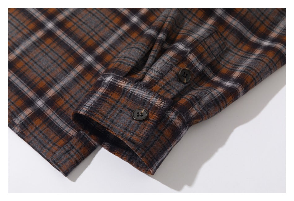 Close-up of a brown, charcoal, and cream plaid shirt cuff with two dark buttons.