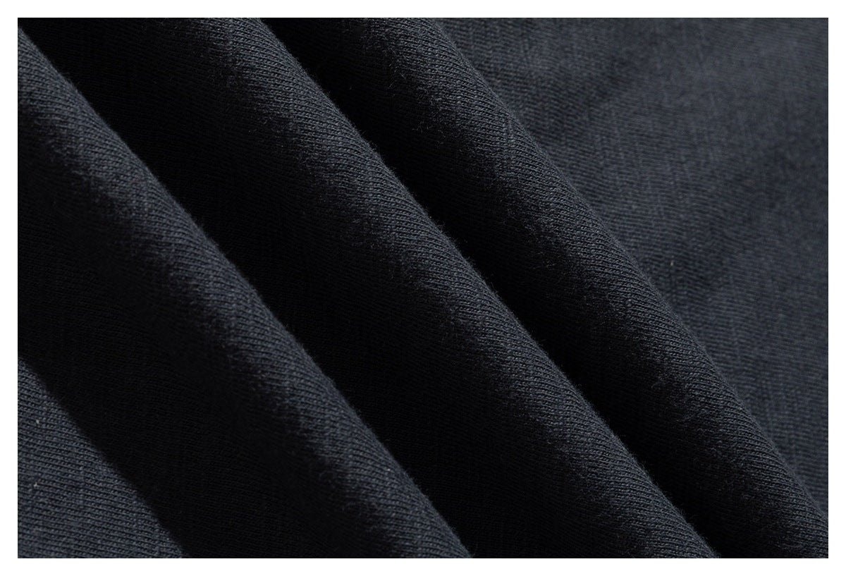 Close-up of dark charcoal fabric gathered into folds, showing its fine surface texture.