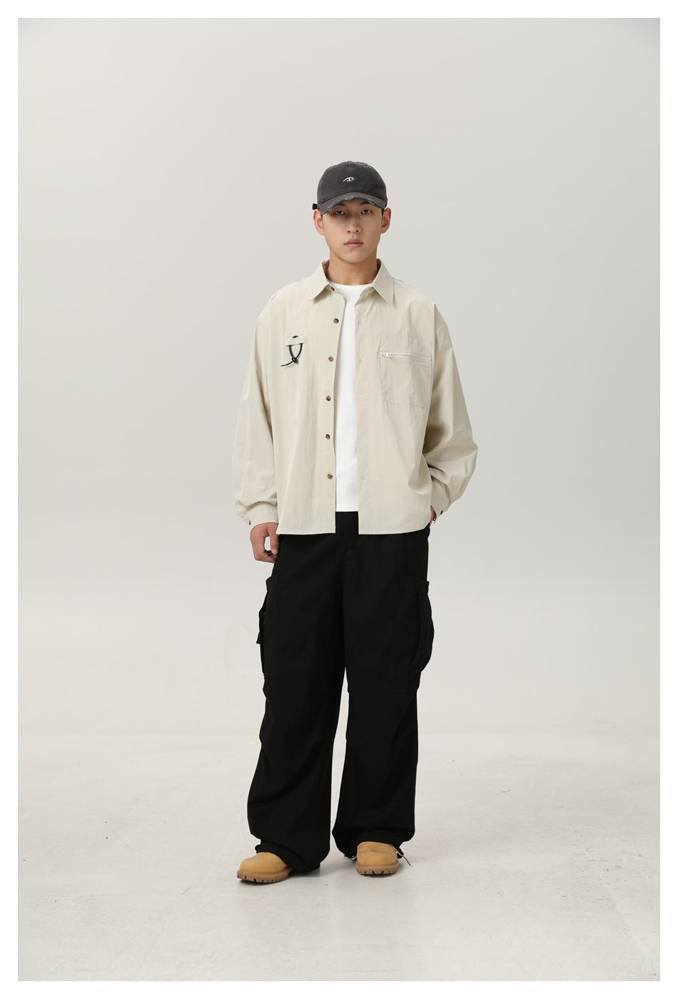 Front view of a model wearing an ivory button-up shirt with a zip chest pocket and black cargo pants.