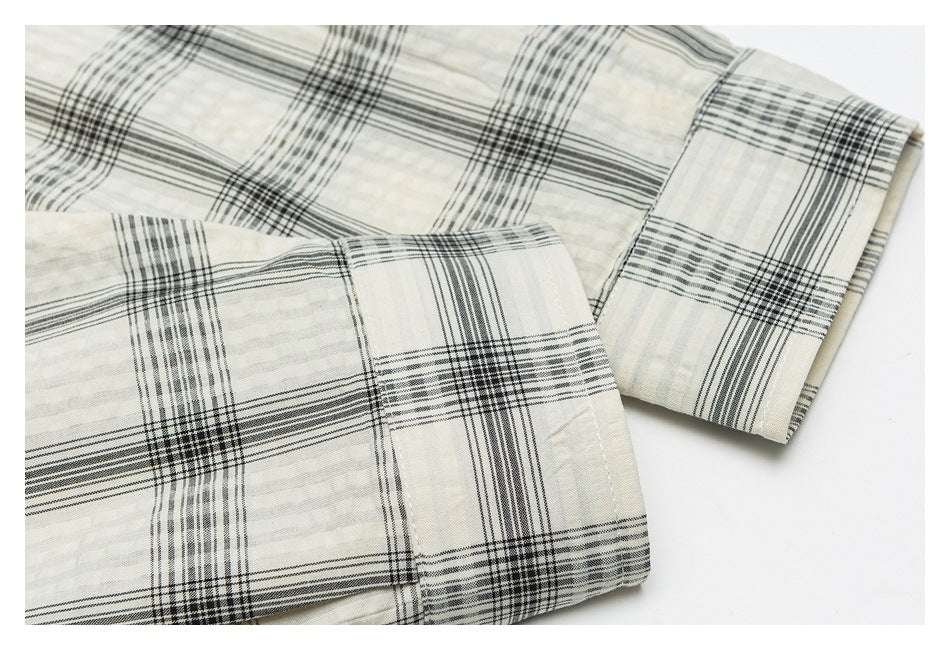 Close-up of the ivory plaid shirt's sleeve and buttoned cuff.