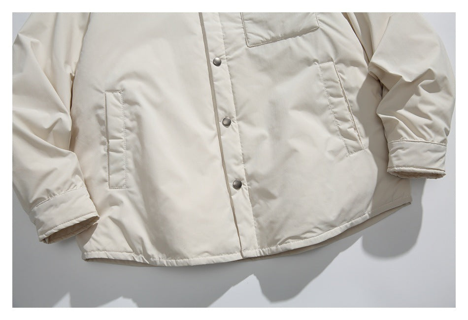 Close-up of the cream jacket's lower front, showing snap buttons, slanted hand pockets, cuffs, and hem.