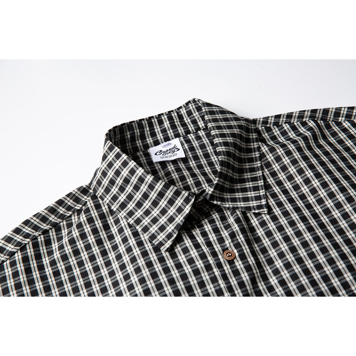 Close-up of a black-and-white plaid short-sleeve shirt collar, neckline, and brown buttons.