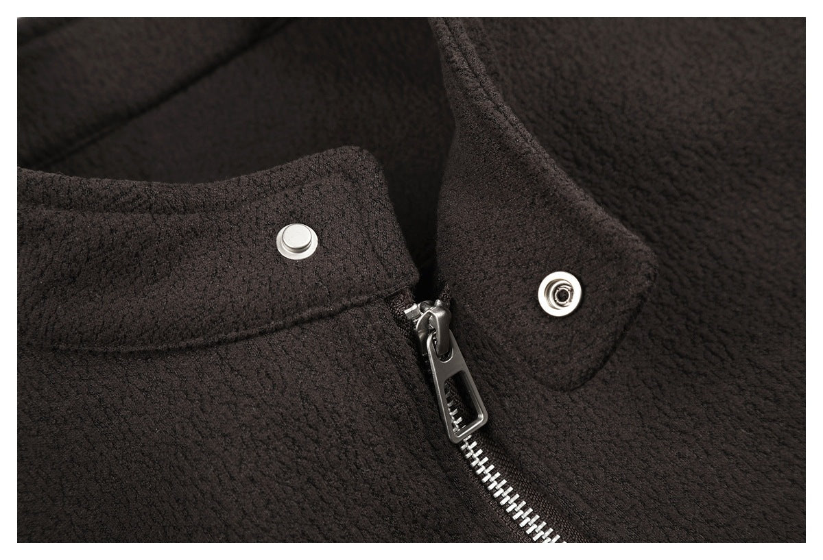 Close-up of a dark brown textured garment with a silver zipper and snap-fastened collar tab.