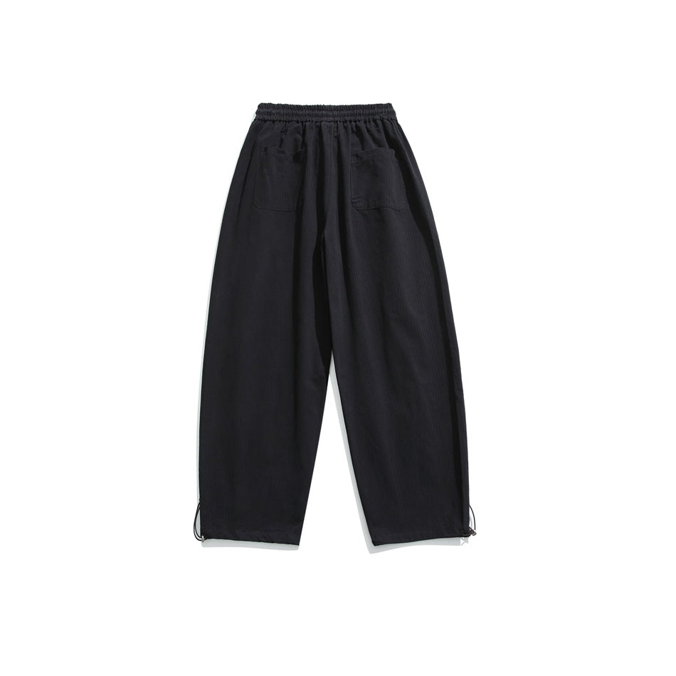 Back view of black wide-leg trousers with an elastic waist, two patch pockets, and adjustable ankle cords.