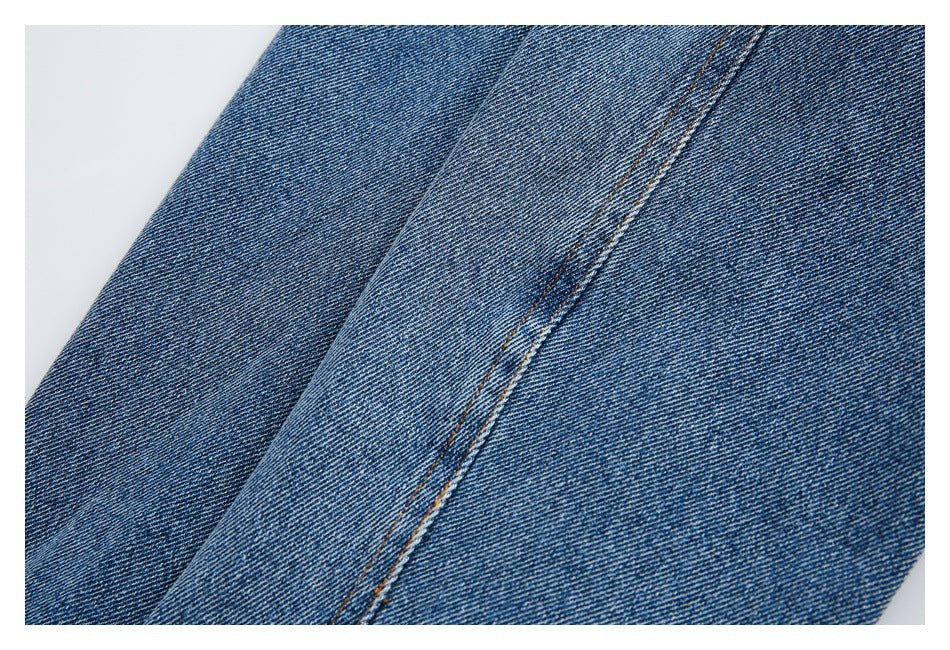 Close-up of a blue denim seam with parallel orange stitching.