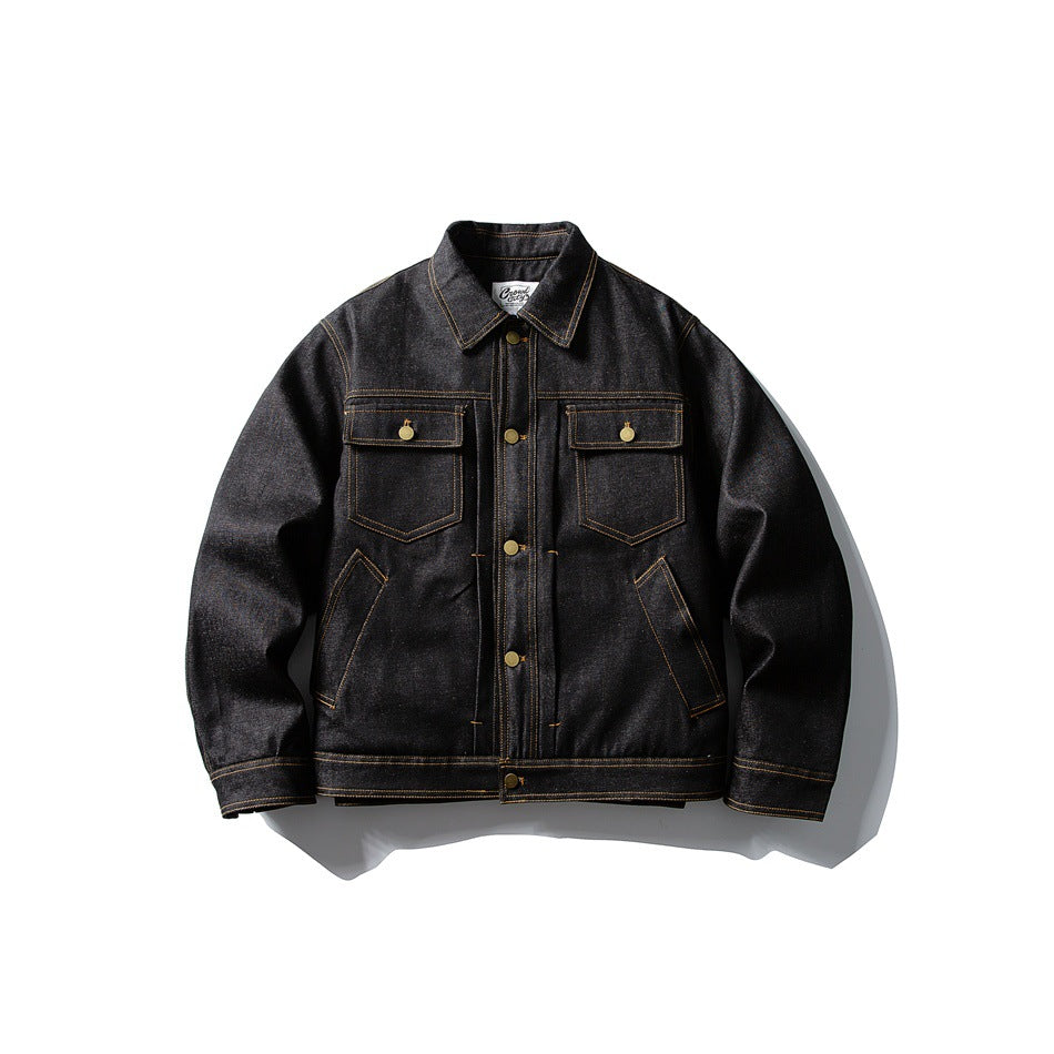 Black denim-look trucker jacket front view with chest flap pockets, brass buttons and golden-tan topstitching