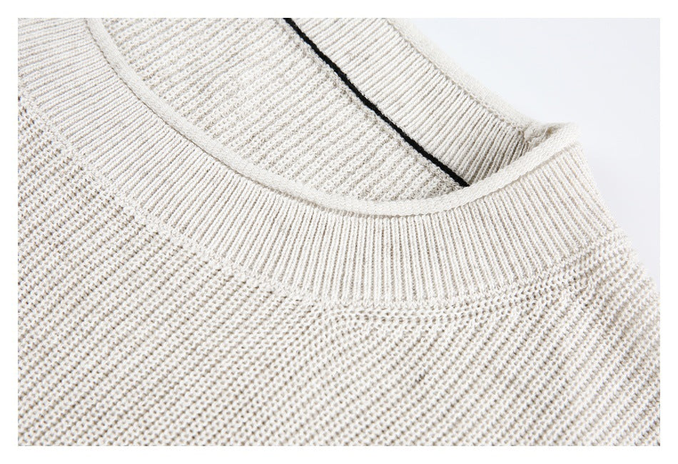 Close-up detail of the ivory sweater's ribbed crewneck collar and textured knit.