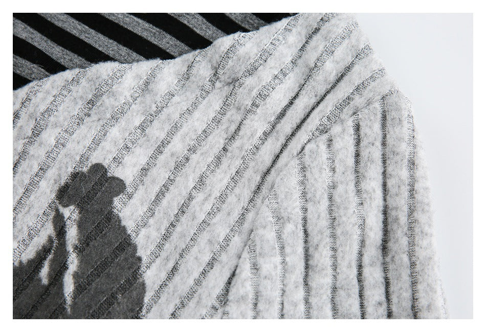 Close-up of a light gray fuzzy garment with narrow dark stripes and a black printed graphic.