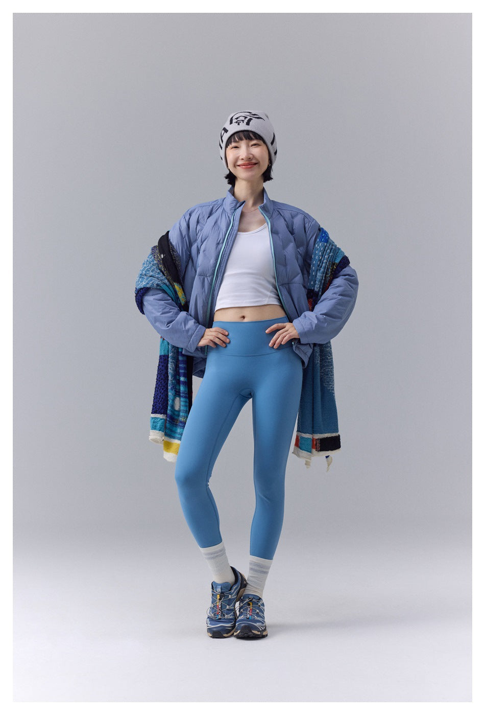 Model wearing an open light blue quilted jacket with turquoise zipper trim; front view.