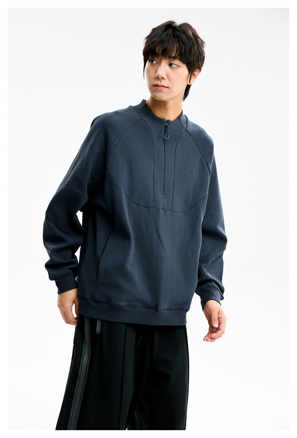Model wearing a dark navy quarter-zip sweatshirt with a stand collar, curved chest seams, and ribbed cuffs.