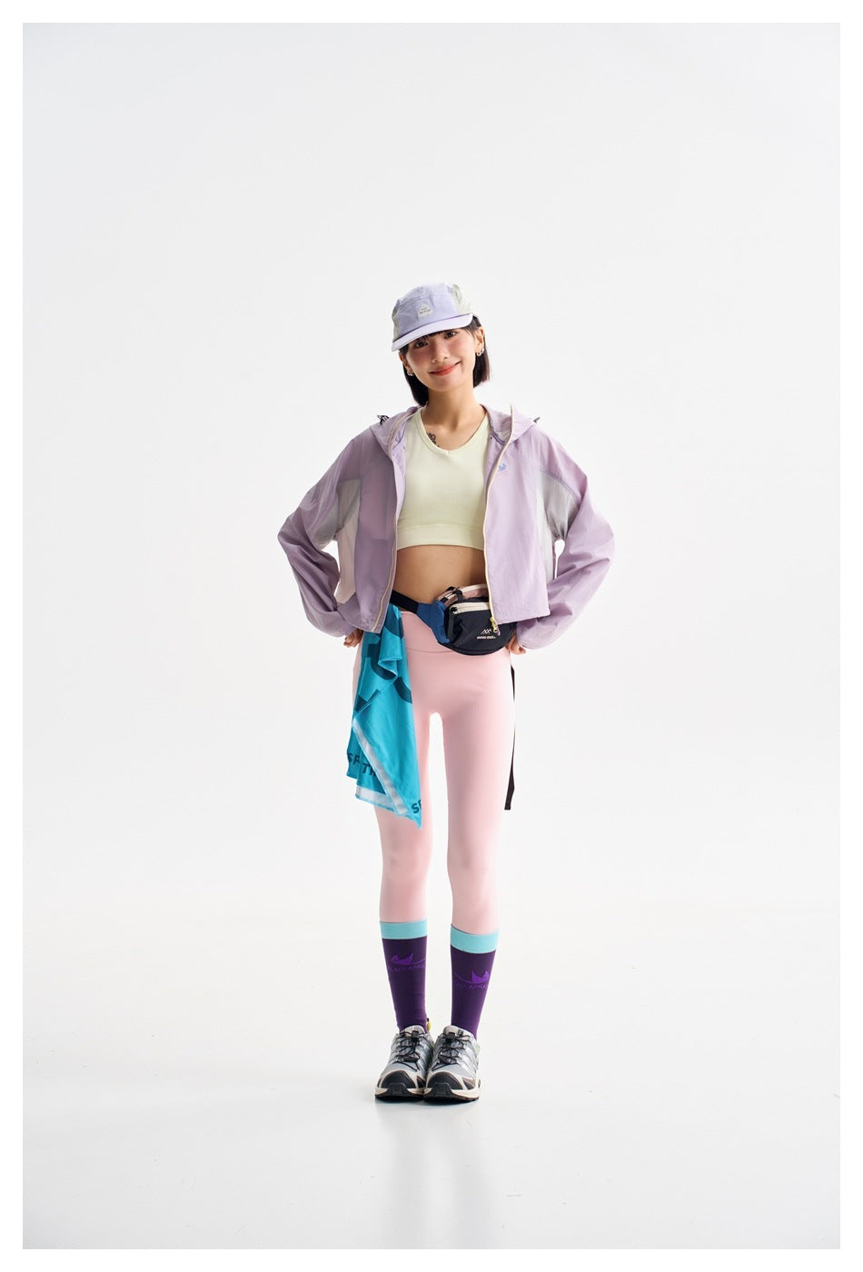 Model wearing a cropped lavender jacket, pale yellow crop top, and light pink leggings.