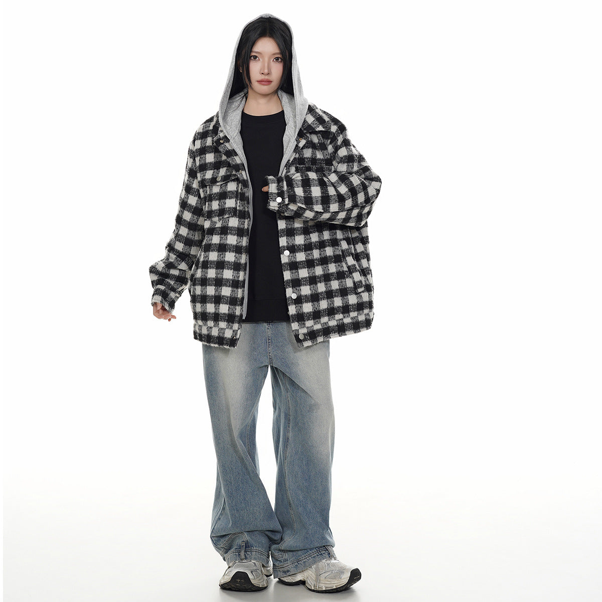 Front view of a model wearing an open black-and-white plaid hooded jacket with loose blue jeans.
