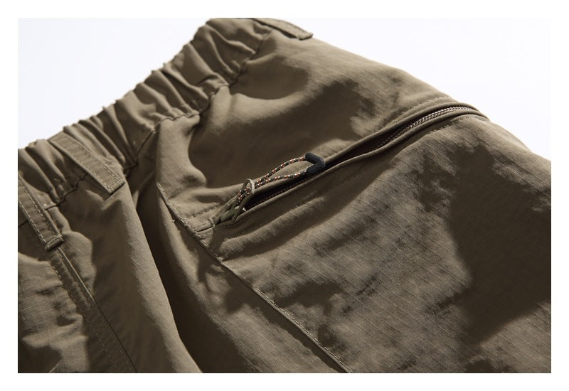 Close-up of an elastic waistband and zippered pocket on an olive-brown garment.