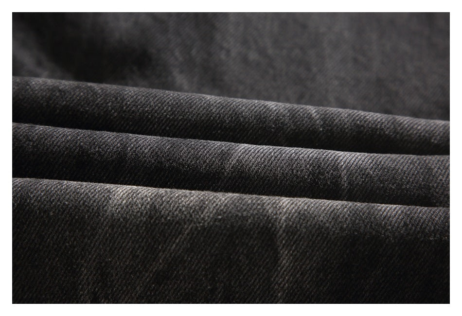 Close-up of dark charcoal denim fabric arranged in soft folds.