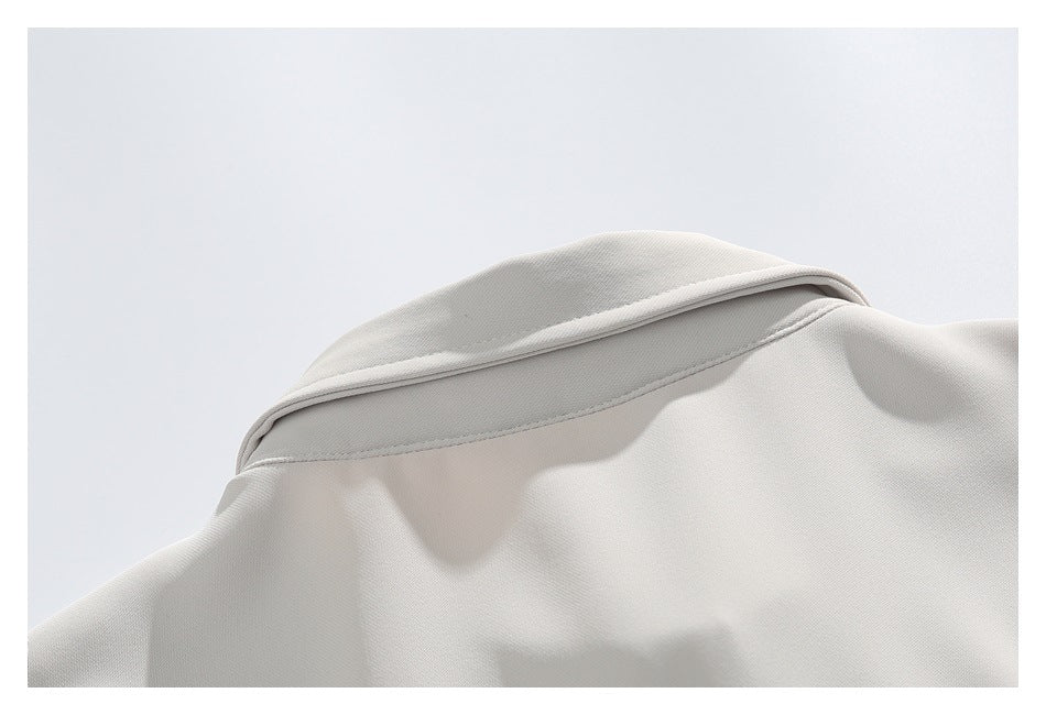 Close-up of the folded collar and stitching on an off-white garment.