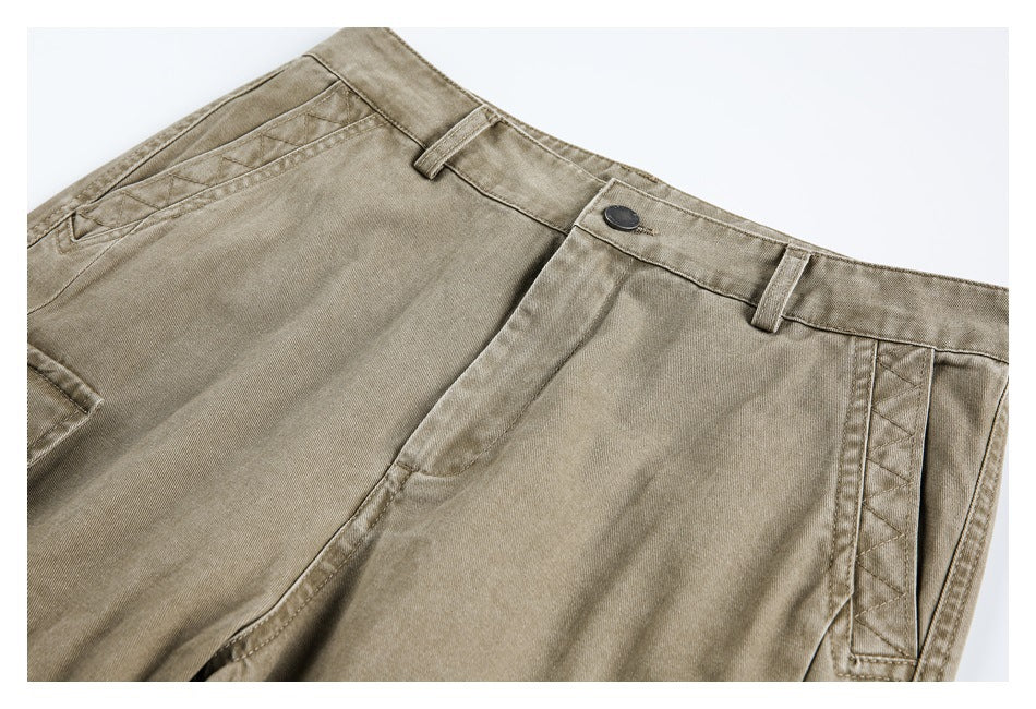 Close-up of taupe trousers showing the waistband, dark button, belt loops, and angled pocket seams.