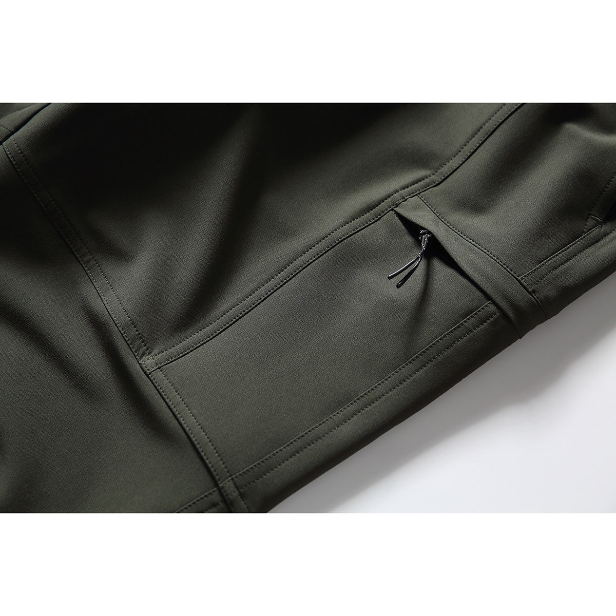 Close-up of dark olive pants showing a stitched panel and a small zippered pocket.