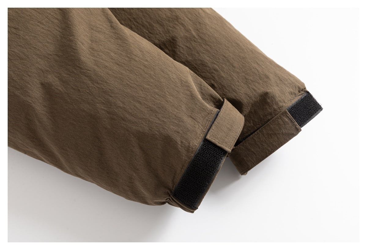 Close-up of a brown jacket sleeve cuff with a black hook-and-loop adjustment tab.